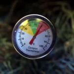 Close-up of a compost thermometer showing active temperature in a compost pile.