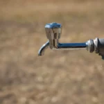 Close-up of a metal water faucet in an outdoor setting, highlighting its rustic charm and simplicity.
