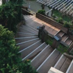 Explore the elegance of a wooden staircase surrounded by lush greenery in an outdoor garden.