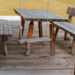 A rustic wooden bench and swing set on a sunny patio in Sankt Ulrich, Italy.