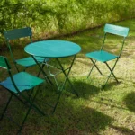 Bistro table and chairs set in a sunny garden with vibrant green surroundings.
