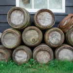 A stack of vintage wooden beer barrels outside a rustic building in Zaandam, Netherlands.