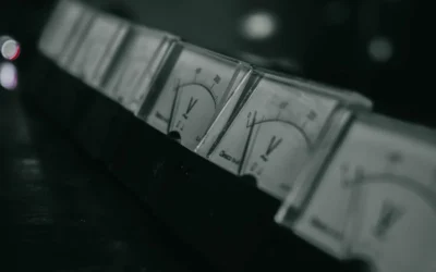 Close-up of vintage analog voltage meters in a dark industrial setting with a moody atmosphere.