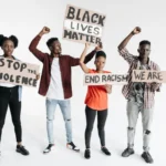 Four adults holding protest signs advocating against racism and violence on a white background.